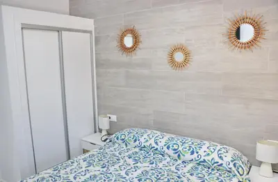 a bedroom with a bed and two mirrors on the wall at Chalet Veron in Conil de la Frontera