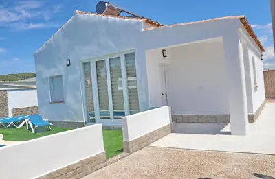 a white house with a door and a chair at Chalet Veron in Conil de la Frontera