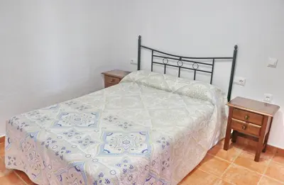 a bedroom with a bed and a night stand with a table at Chalet Peñuelas in Conil de la Frontera