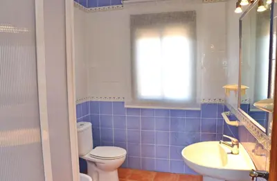 a blue tiled bathroom with a toilet and a sink at Chalet Peñuelas in Conil de la Frontera