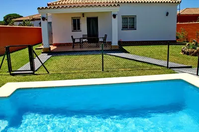 a blue swimming pool in front of a house at Chalet Cala de Roche in Roche