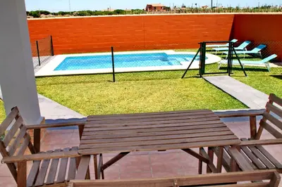 a wooden bench next to a pool with a swing at Chalet Cala de Roche in Roche