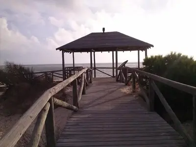 a wooden boardwalk leading to a gazebo on the beach at Apartamento con Terraza,a 100m playa Costilla y Frente al Castillo in Rota