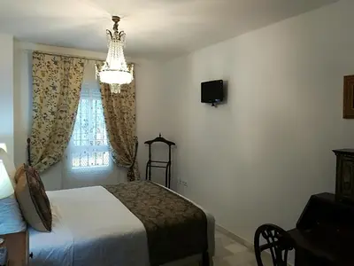 a bedroom with a bed and a chandelier and a window at Rota playa Calle Puyana in Rota