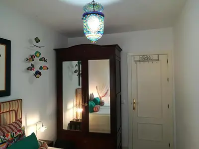 a room with a bedroom with a mirror and a chandelier at Rota playa Calle Puyana in Rota