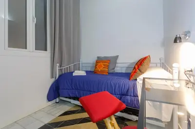 a small bedroom with a bed and a red chair at La PEPA1812 by Cadiz4Rentals in Cádiz