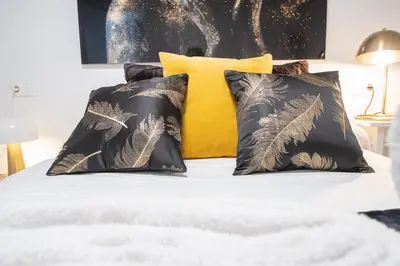 a bed with two black pillows and a yellow pillow at Apartamento Arco de los Blanco in Cádiz