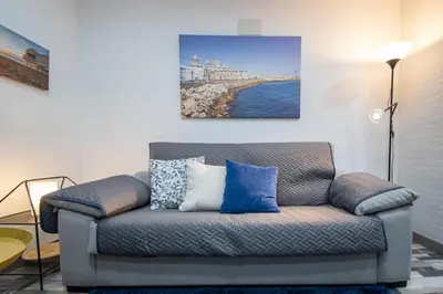 a couch in a living room with a painting on the wall at Apartamento Arco de los Blanco in Cádiz