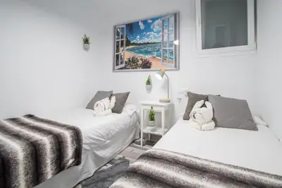 two beds in a room with white walls at Apartamento Arco de los Blanco in Cádiz