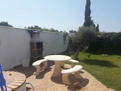 a patio with a table and two chairs and a grill at Alojamientos Rurales Inma in Conil de la Frontera