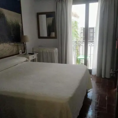 a bedroom with a bed and a large window at Hostal Gran Capitan in Chipiona