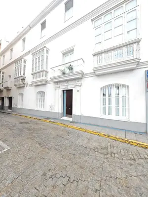 an empty street in front of a white building at El Estudio del Marqués Little Apartments in Cádiz