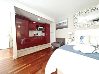 a bedroom with a bed and a chair and a mirror at El Estudio del Marqués Little Apartments in Cádiz