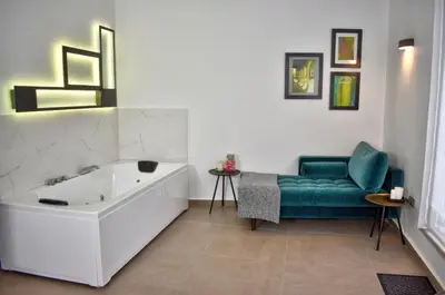 a bathroom with a tub and a green couch at Home Apartments Jerez in Jerez de la Frontera