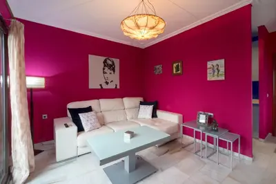 a living room with a white couch and a pink wall at Atico soleado y céntrico in Cádiz
