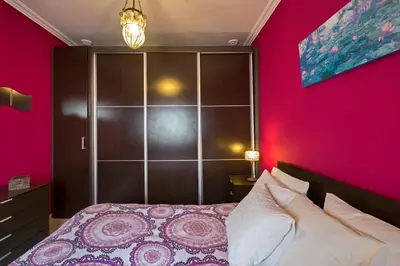 a bedroom with a pink wall and a bed at Atico soleado y céntrico in Cádiz