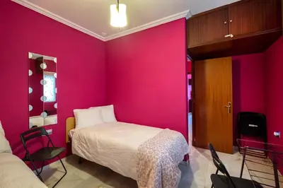 a room with a bed and a pink wall at Atico soleado y céntrico in Cádiz