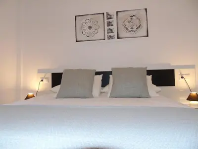 a bedroom with a white bed with three pictures on the wall at Atiko La Vista in Arcos de la Frontera