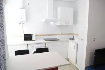 a white kitchen with white cabinets and a white table at Fantástico Piso, Junto a Playa y Pleno Centro in Cádiz