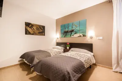 two beds in a room with a painting of a ship at Gades Suite in Cádiz