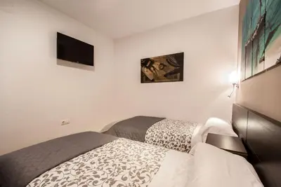 a white bedroom with a bed and a television at Gades Suite in Cádiz
