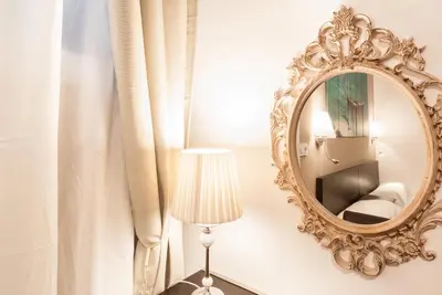 a mirror on a wall with a lamp and a curtain at Gades Suite in Cádiz