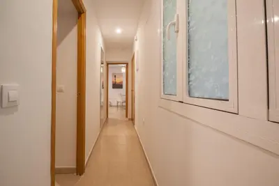 a long hallway with white walls and a window at Gades Suite in Cádiz