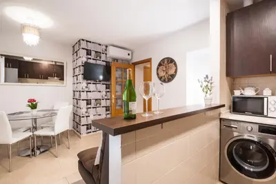 a kitchen with a washing machine and a dining room at Gades Suite in Cádiz