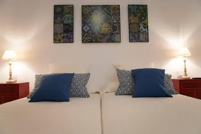 a bedroom with a white bed with blue pillows at Apartamento Rosario 49 in Cádiz