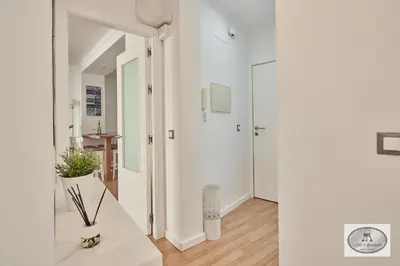 a hallway with white walls and a white table with a plant at Dulce Arbolí Little Apartments in Cádiz