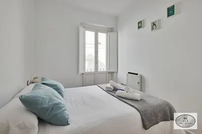 a white bedroom with a bed with towels on it at Dulce Arbolí Little Apartments in Cádiz
