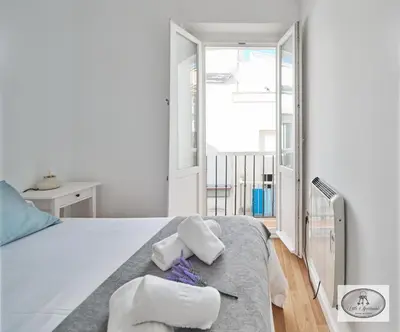 a white bedroom with a bed with towels on it at Dulce Arbolí Little Apartments in Cádiz