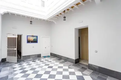 a room with a white wall and a checkered floor at Dulce Arbolí Little Apartments in Cádiz
