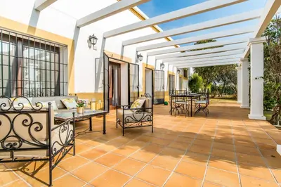 an outdoor patio with tables and chairs and a pergola at Vivienda Rural Olivar de San Telmo in Arcos de la Frontera