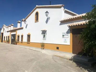 a white and yellow building with a garage at Vivienda Rural Olivar de San Telmo in Arcos de la Frontera