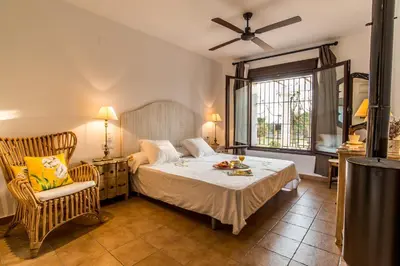 a bedroom with a bed and a chair and a window at Vivienda Rural Olivar de San Telmo in Arcos de la Frontera