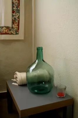 a green glass vase sitting on a table with a candle at Casas Lomas II in Arcos de la Frontera
