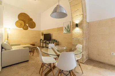a dining room with a glass table and white chairs at Charming Apartment in Jerez de la Frontera