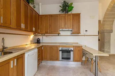 an empty kitchen with wooden cabinets and a table at Charming Apartment in Jerez de la Frontera