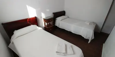 two beds in a small room with white sheets at Casas Turísticas Bajamar in Sanlúcar de Barrameda