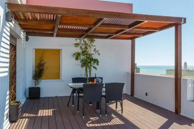 a patio with a table and chairs on a deck at Atico FULL Balcony by Cadiz4Rentals in Cádiz