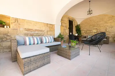 a patio with a couch and chairs and a table at Cream Loft Siente Jerez Parking Incluido in Jerez de la Frontera