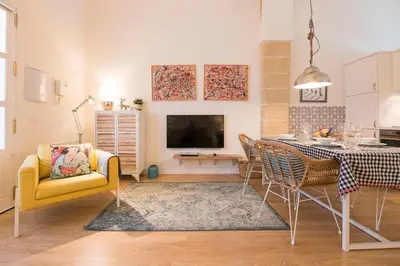 a living room with a dining table and a tv at Cream Loft Siente Jerez Parking Incluido in Jerez de la Frontera