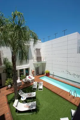 a backyard with a swimming pool and a palm tree at La Alcoba del Agua Hotel Boutique in Sanlúcar de Barrameda