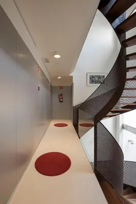 a hallway with a spiral staircase and a red rug at La Alcoba del Agua Hotel Boutique in Sanlúcar de Barrameda
