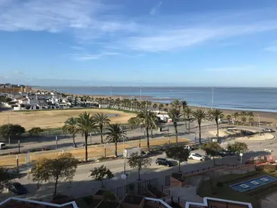 a view of a beach with palm trees and the ocean at Infantes 8-4-30 in Sanlúcar de Barrameda