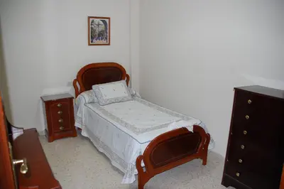 a small bedroom with a bed and a dresser at Casa Rosalia in Sanlúcar de Barrameda