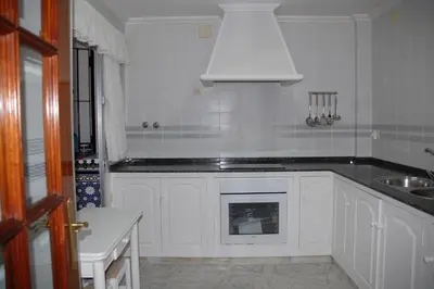 a kitchen with white cabinets and a sink and a stove at Casa Rosalia in Sanlúcar de Barrameda