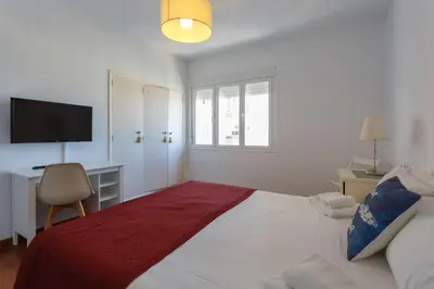 a white bedroom with a bed and a desk with a television at OCEANO Family Home free parking by Cadiz4Rentals in Cádiz
