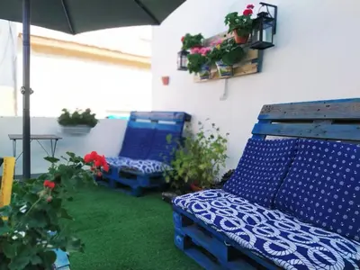 a patio with two blue chairs and an umbrella at Hostal Casa Nautilus in Cádiz